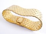 a close up of a gold bracelet on a white surface
