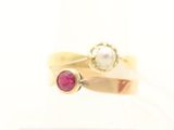 un gros plan d'une bague en or sertie d'une perle et d'un rubis