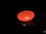 a glowing orange object in the dark with a reflection on the ground