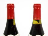 two bottles of red wine are sitting on a white surface