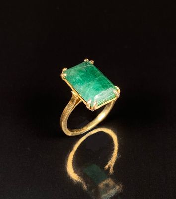 un gros plan d'une bague avec une pierre verte sur un fond noir