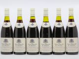 six bottles of wine are lined up on a white surface
