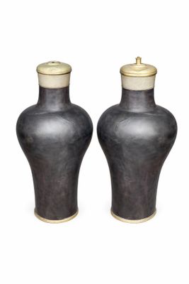 une paire de vases noirs avec des couvercles dorés sur fond blanc