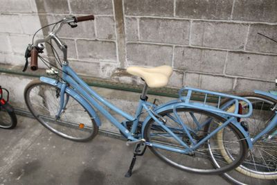 a blue bicycle that is parked next to a brick wall
