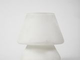 une lampe blanche posée sur une table près d'un mur blanc