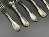 six fourchettes et cuillères en argent sont alignées sur une table