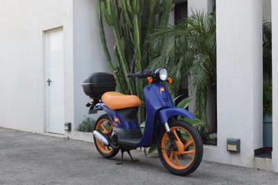 a blue and orange scooter parked in front of a building