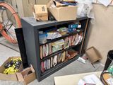 a black bookcase with many files and boxes on it