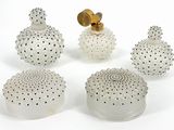 four white glass vases with gold accents on a white surface
