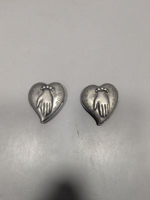 une paire de boucles d'oreilles en argent en forme de cœur, ornées de mains