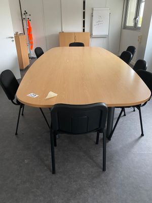 une grande table en bois avec des chaises noires dans une pièce