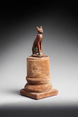 une petite statue représentant un chat assis sur un socle en bois