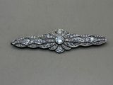 a close up of a diamond broochle on a gray surface