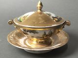 a gold plate with a lid and a saucer on it