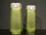 deux vases verts posés sur une table, sur fond noir