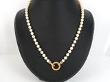 a necklace with pearls and a gold ring on a mannequin