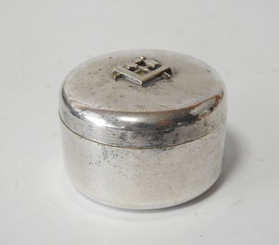 une vieille boîte en argent ornée d'une croix, posée sur une surface blanche