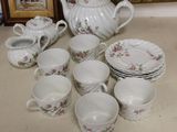 many cups and saucers and a teapot on the table