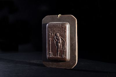 an image of a bronze pendant with a picture of a man holding a sword