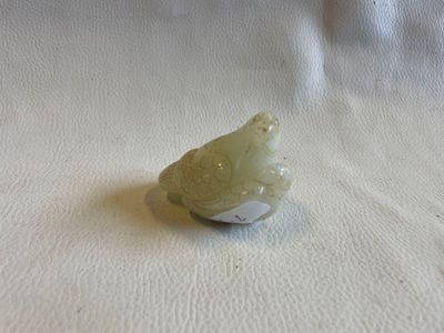 une petite figurine représentant un oiseau posé sur une surface blanche