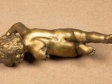 a small bronze statue of a baby laying on its back