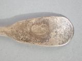 a silver spoon with a flower on it on a table