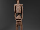 une sculpture représentant un squelette tenant une tête humaine