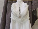 a white wedding dress hanging on a hanger in front of a brick wall