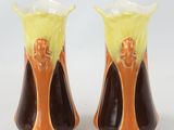 pair of orange and black vases with a yellow flower on the top