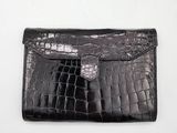 an image of a black crocodile skin wallet with a silver clasp