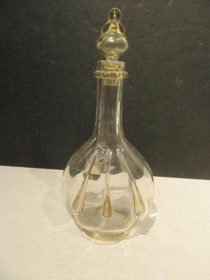 a clear glass bottle with a gold top on a table