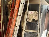 une échelle appuyée contre un mur, à côté d'un tas d'outils