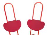 two red chairs sitting next to each other on a white surface