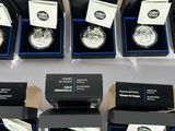 six boxes of silver coins are sitting on a white surface