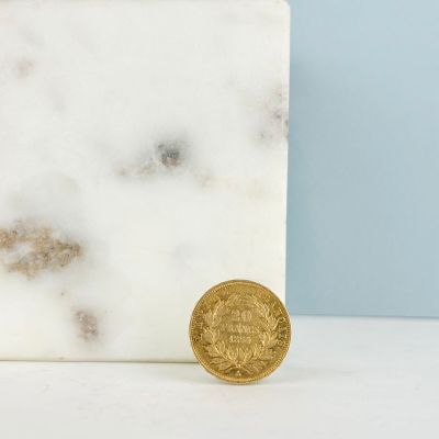 une pièce d'or posée à côté d'un bloc de marbre blanc