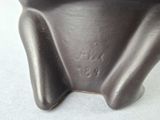 a close up of a black vase on a white surface