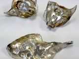 three pieces of silver metal are sitting on a white surface