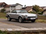 une voiture argentée qui roule sur la route devant une maison