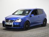 Une Volkswagen Golf bleue est garée dans une pièce dont le sol est en damier.