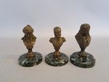 three brass figurines of a man and a woman on marble bases