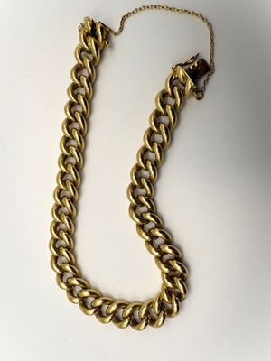 gros plan d'un collier à chaîne en or sur une surface blanche
