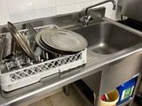 un évier en inox contenant de la vaisselle et des ustensiles