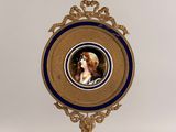 a gold frame with a picture of a woman and a dog on it