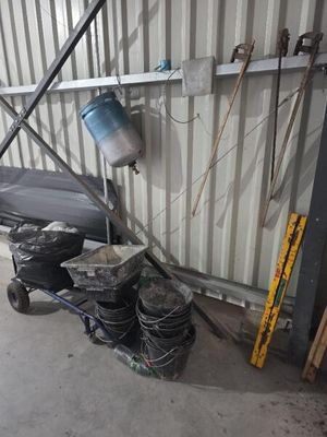 Plusieurs seaux de peinture sont empilés sur un chariot devant un immeuble.