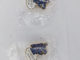 three blue and white pins in plastic bags on a white surface