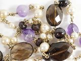 purple and white pearls and amethorate necklace on a white surface