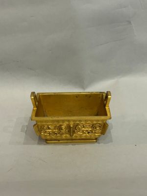 a close up of a gold planter on a white surface