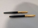 deux stylos noirs et dorés posés sur une table blanche