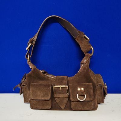 a brown sued purse with two buckles on a white surface