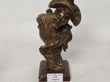 une statue en bronze d'un homme avec un chapeau sur la tête
